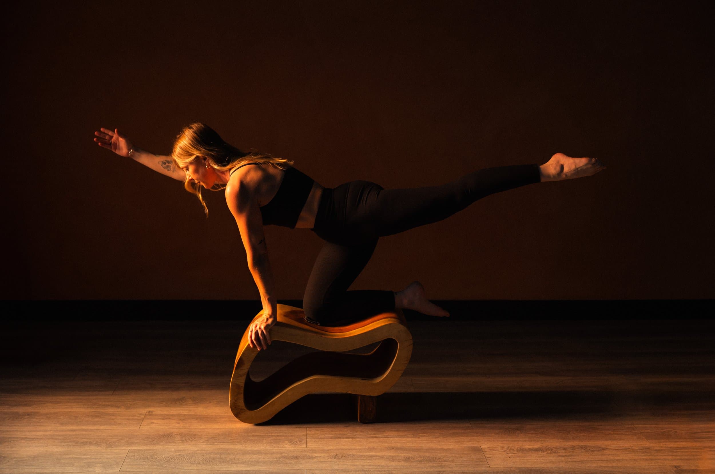 A client balanced on the curved timber arc in the studio